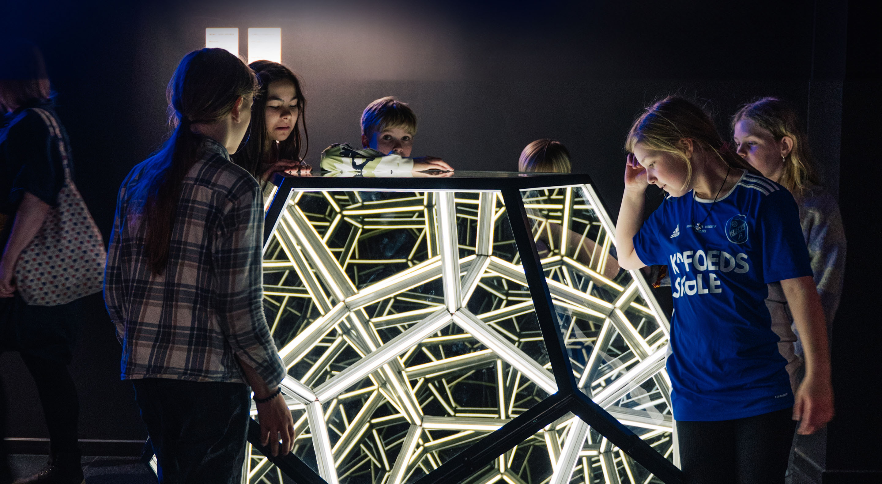 School children are looking into the Infinity Dodecahedron at Museum of Illusions.