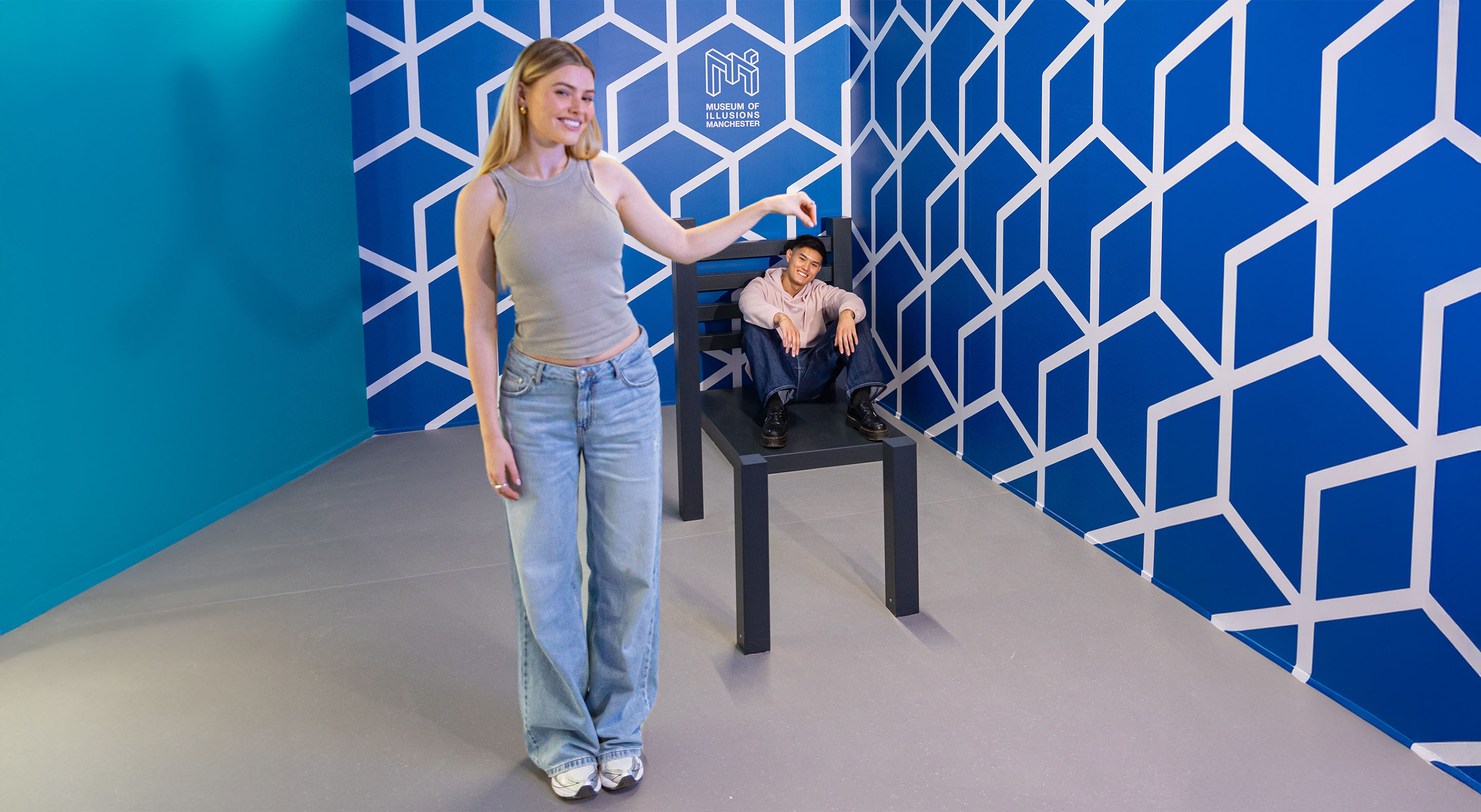 A visitor sitting in the Beuchet Chair looks disproportionately small compared to another visitor standing next to it.