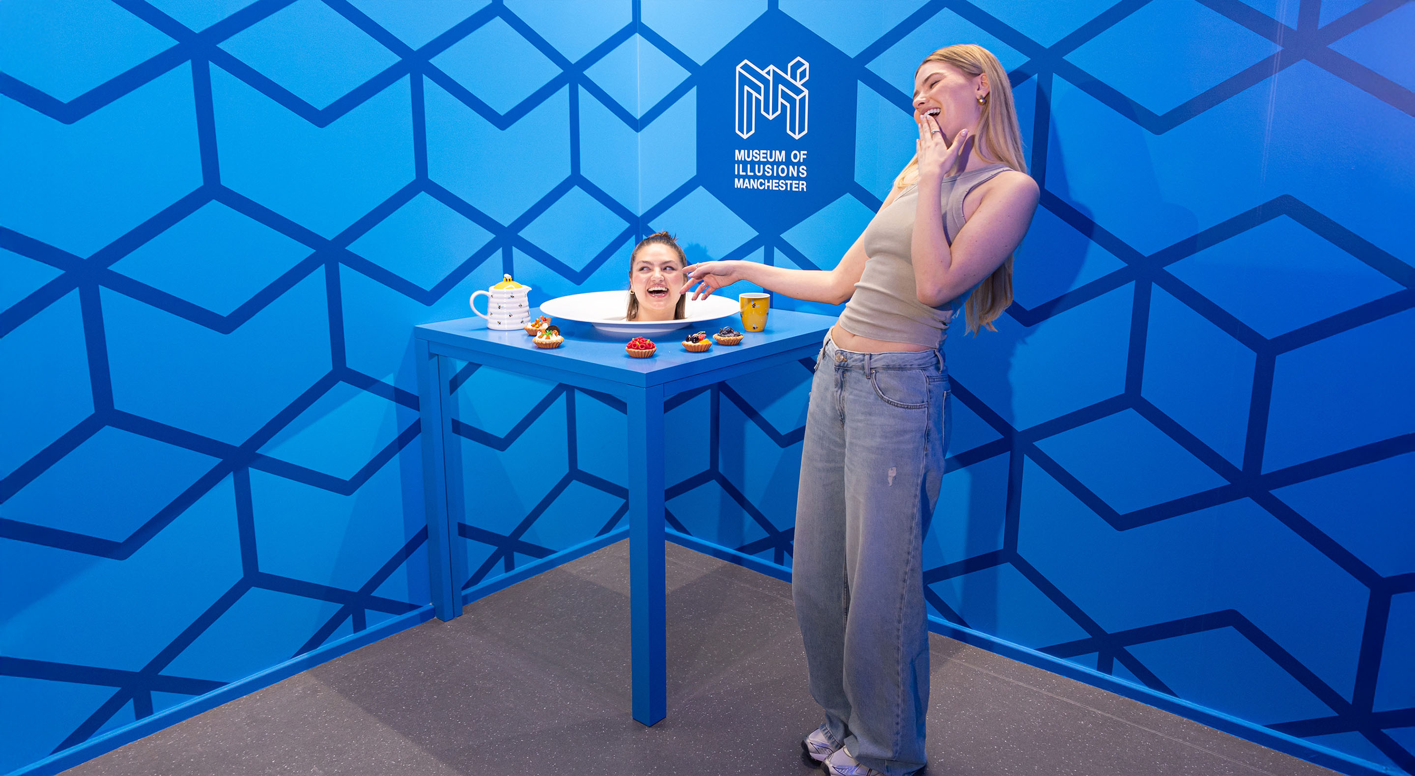 Two young women interacting with the classic Head on a Platter illusion.