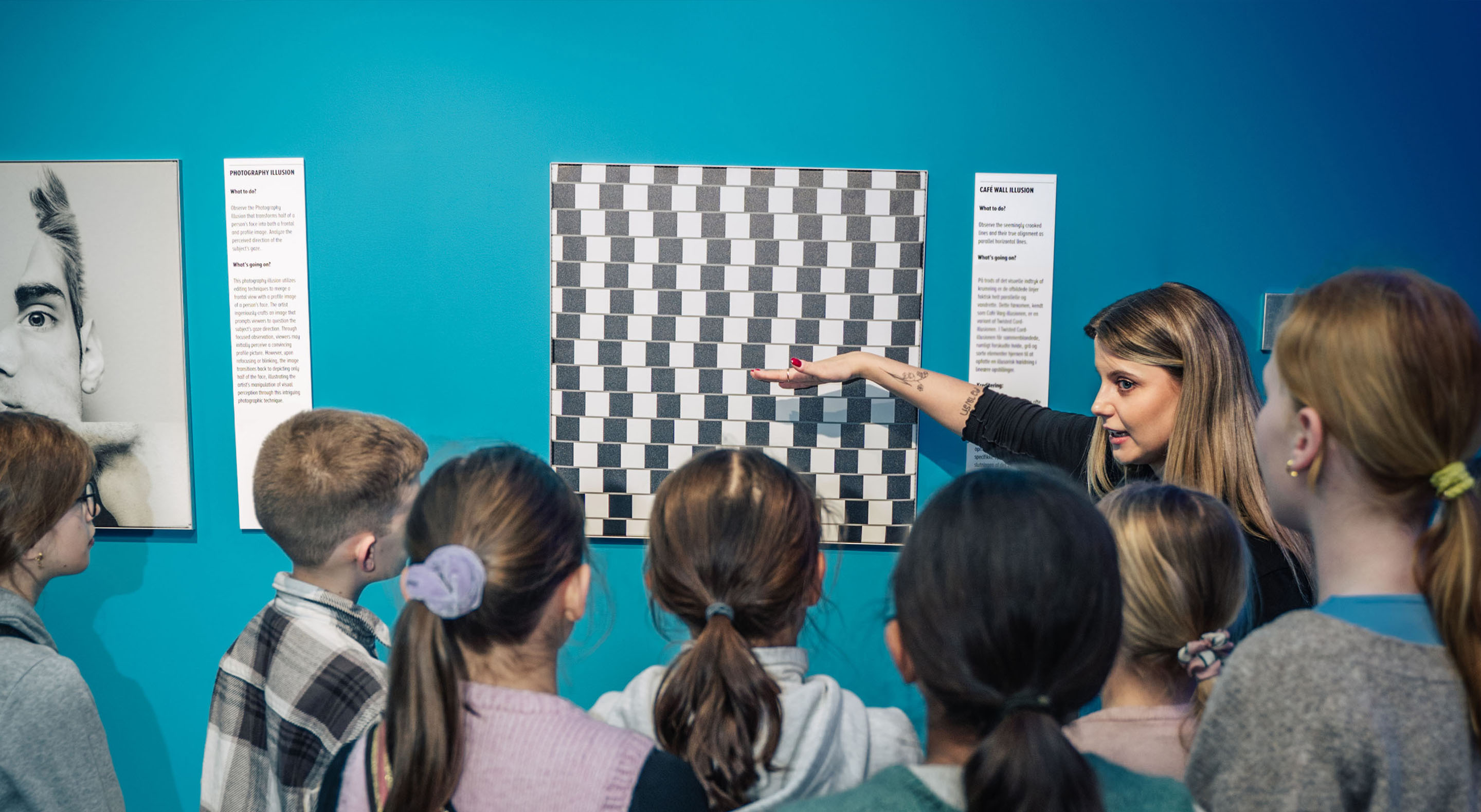 An educator is explaining an optical illusion to a group of school children.