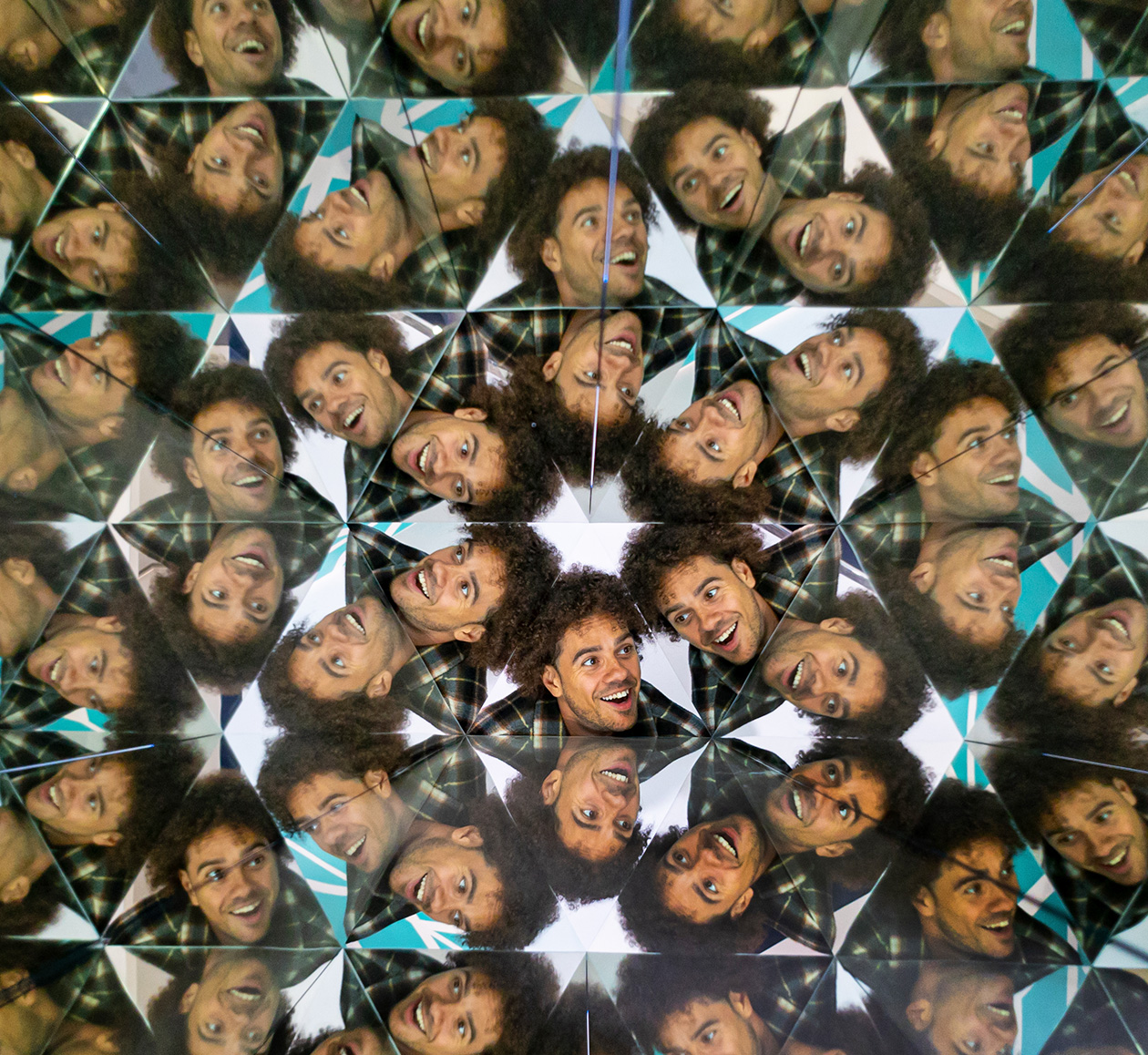 Visitor at Museum of Illusions in the Kaleidoscope exhibit with a face multiplied in a kaleidoscopic pattern.