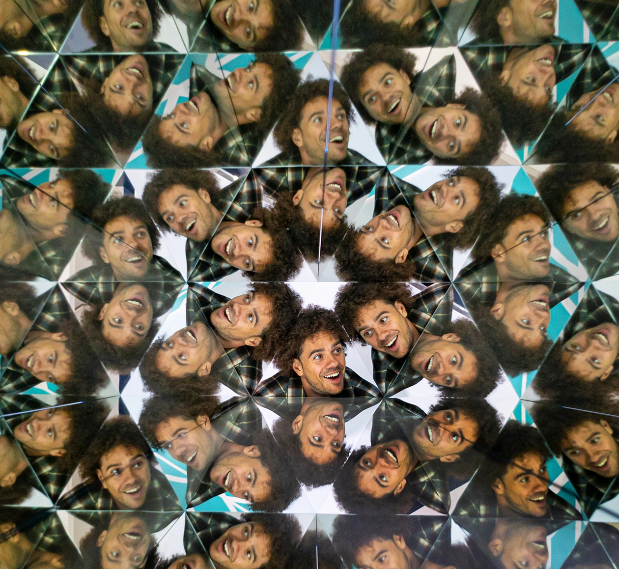 Visitor at Museum of Illusions in the Kaleidoscope exhibit with a face multiplied in a kaleidoscopic pattern.