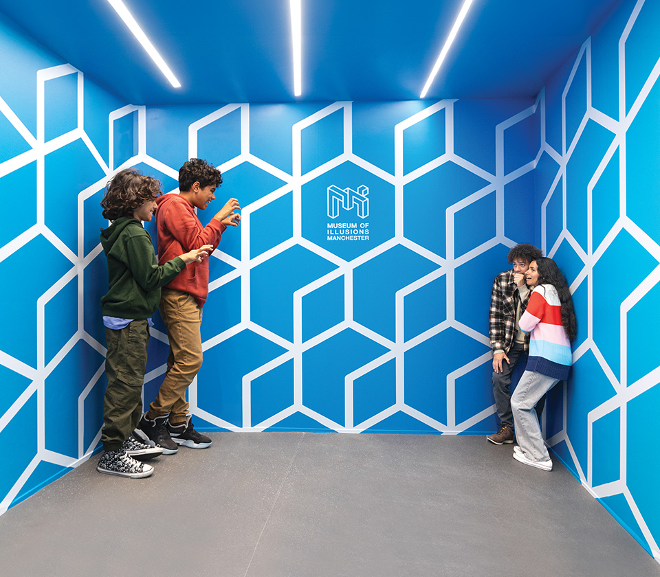 Two children in one corner of the Ames Room appear much larger than their parents standing in the opposite corner.