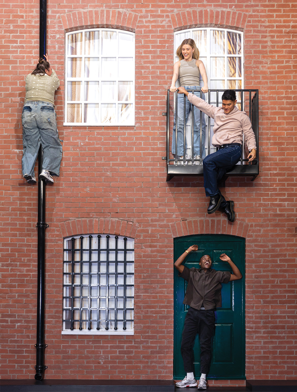 Visitors at Museum of Illusions interacting with the Building Illusion, appearing to climb a building facade.